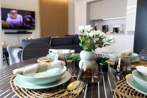 a dining room table with white dishes and flowers on it at Sunny Haven Wave SEA VIEW 8th Floor in Międzyzdroje