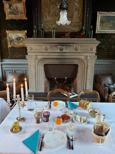 Una mesa con comida y velas con chimenea. en Château de Contay Guesthouse - 1753, en Contay