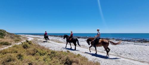 three people riding horses on a beach near the ocean at Ashore - Beachfront Paradise in St Helena Bay