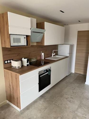 une cuisine avec des armoires blanches, un évier et un micro-ondes dans l'établissement « L’Observatoire » 6 personnes, à Bandol