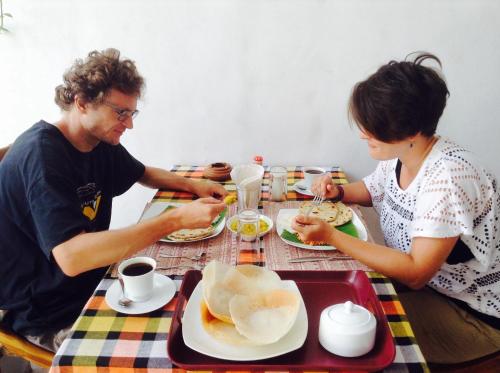 a man and woman sitting at a table eating food at Sanctuary Cove Guest House in Polonnaruwa