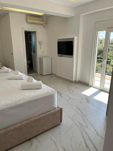 a white bedroom with a bed and a television at Harmony Apartments in Dhërmi