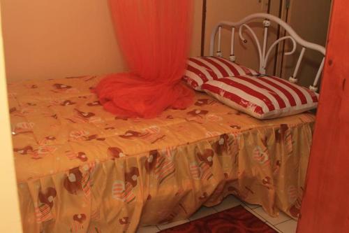 a bed with an orange comforter and two pillows on it at Le carambolier maison avec vue imprenable in La Trinité