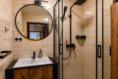 a bathroom with a sink and a shower with a mirror at Apartament Morska Przygoda in Jastrzębia Góra