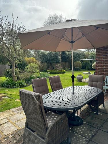 a table with an umbrella on a patio at 'BRAMLEY FALL COTTAGE' NEW AVAILABILITY - Attached Cottage,3 Bedrooms-1 on ground level, SLEEPS 6-2 Bathrooms, Wittering and Chichester easy drive, Child friendly,Small Breed Dog Friendly 2 max, Parking-EV Point in Chichester