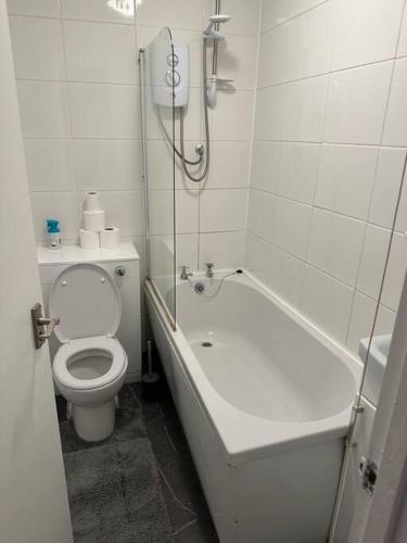a white bathroom with a toilet and a bath tub at Lovely Modern One bedroom Flat close to station in Belvedere