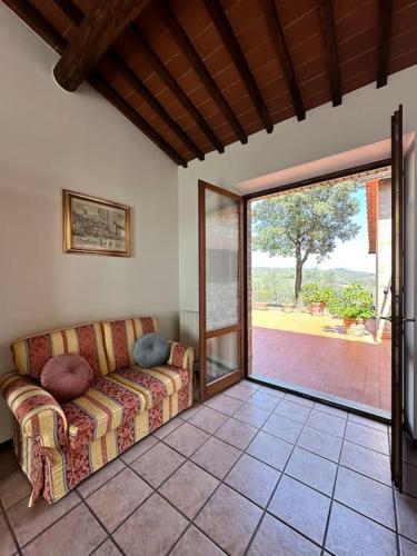 a living room with a couch and a sliding glass door at Casa il Cipresso in Castelnuovo Berardenga