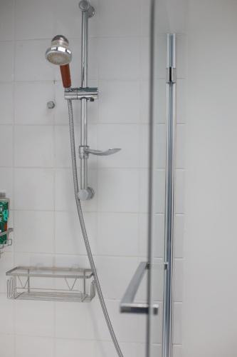 a shower with a hose attached to a wall at A cosy garden flat in a quiet area close to the city centre in Bristol