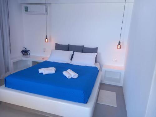 a bedroom with a blue bed with towels on it at Blue Waves Suite Mykonos in Kalafatis