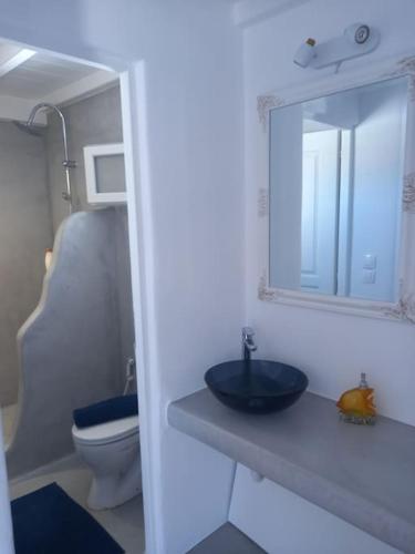 a bathroom with a sink and a toilet and a mirror at Blue Waves Suite Mykonos in Kalafatis