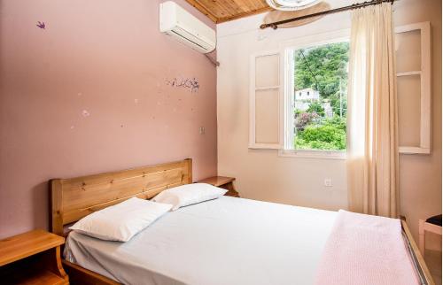 a bedroom with a bed and a window at The Grapevine Rooms in Póros Kefalonias