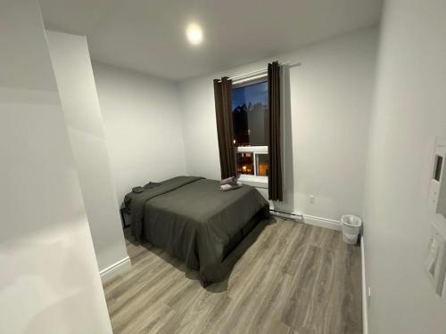 um quarto com uma cama num quarto com uma janela em Appartement 2 chambres - 202 em Montreal