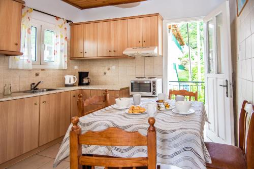 a kitchen with a table with chairs and a microwave at The Grapevine Rooms in Póros Kefalonias