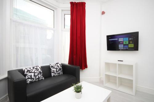 a living room with a black couch and a window at BARTON BEACHSIDE APARTMENTS - Free Parking, Modern Chic, Central Beach Location, Some Sea Views - Families Couples or Over 23 years in Blackpool