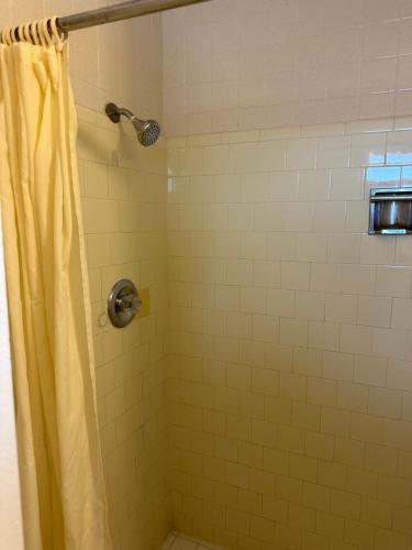 a shower with a yellow shower curtain in a bathroom at Sands Motel in San Antonio