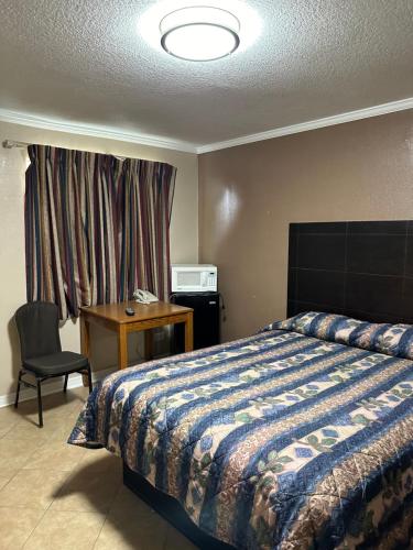 a bedroom with a bed and a desk and a chair at Sands Motel in San Antonio