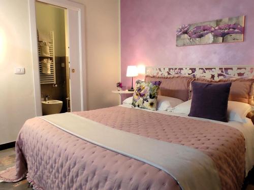 a bedroom with a large bed with a purple wall at Affittacamere Casa Mac & Rose in San Quirico dʼOrcia