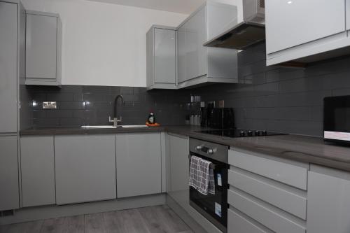 a kitchen with white cabinets and a sink at Modern and Comfy in City Centre PS4 , Free On Street Parking ,Walking Distance To Bus, Train Stations And Shopping Centres in Leicester