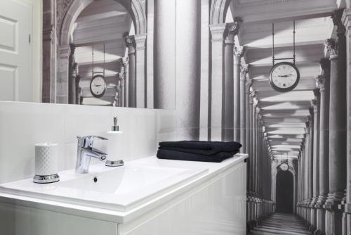 a bathroom with a sink and a mirror and clocks at Apartament Tenczyńska in Krakow