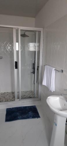 bagno bianco con doccia e lavandino di Shalom Apartments Kalumbila a Musele