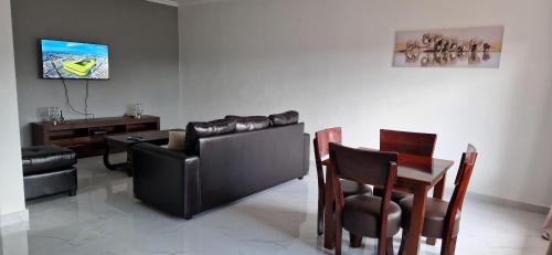 uma sala de estar com um sofá, uma mesa e cadeiras em Shalom Apartments Kalumbila em Musele