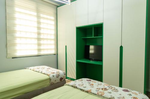 a small bedroom with two beds and a tv at Luxury Lungomare apartament in Vlorë
