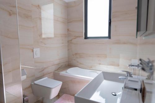 a bathroom with a toilet and a tub and a sink at Luxury Lungomare apartament in Vlorë