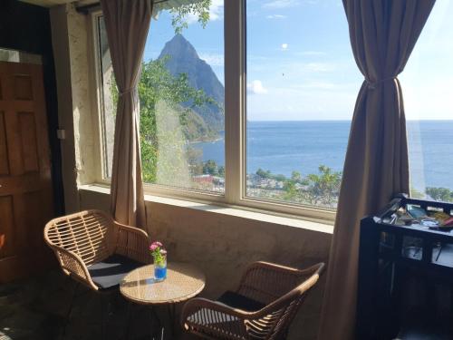 a table and chairs in front of a large window at Green Fig Resort & Spa in Soufrière