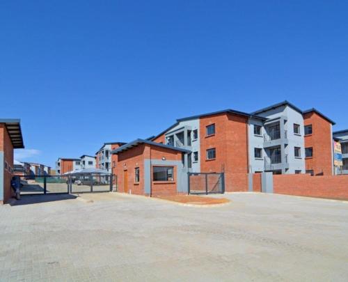 ein leerer Parkplatz vor einem Backsteingebäude in der Unterkunft Saffron Place @ 2bed Apt Midrand in Midrand