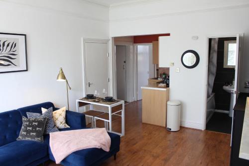 a living room with a blue couch and a kitchen at Flat 5, Westhill in Leeds