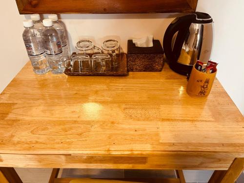 a wooden table with glasses and bottles on it at Villa Pich Boutique with fast WiFi, Khmer Boxing and Classical Khmer Dance Kampot in Kampot