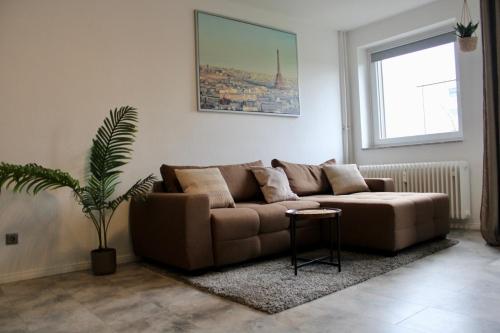 a living room with a brown couch and a plant at RuhrGEbietsquartier - Gemütliche Wohnung in Gelsenkirchen-Buer in Gelsenkirchen