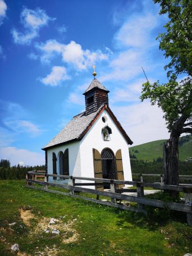 a small white church with a steeple on a field at Almhaus Alpenrose Postalm in Seidegg