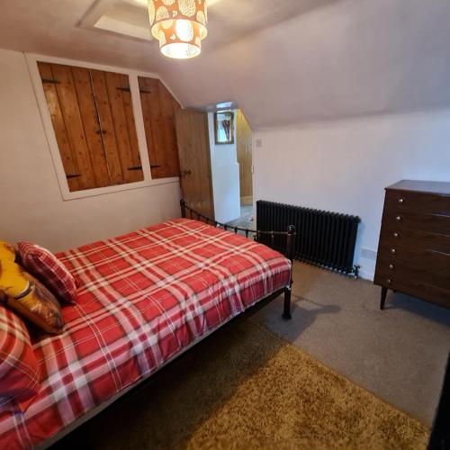 a bedroom with a bed with a red plaid blanket at Ness City Cottage - Attic Apartment in Inverness