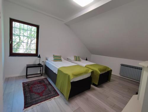 a bedroom with two beds with green sheets and a window at FERA Apartments in Sarajevo