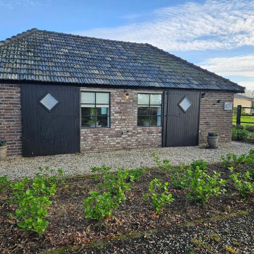 a brick house with a black door and windows at huisje Schouwenberg in Swalmen