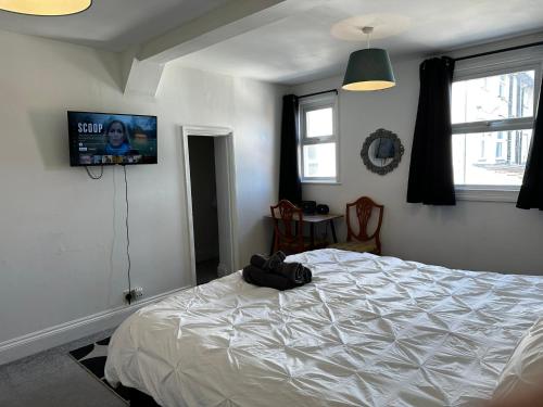 a bedroom with a white bed and a flat screen tv at Cosy entire apartment super king bed near town center in Colchester
