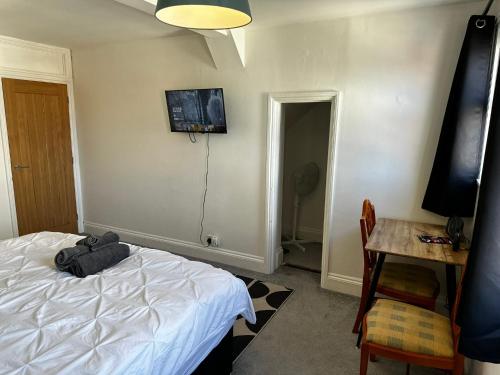 a bedroom with a bed and a desk and a table with a television at Cosy entire apartment super king bed near town center in Colchester