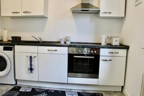 a kitchen with white cabinets and a stove top oven at RuhrGEbietsquartier - Gemütliche Wohnung in Gelsenkirchen-Buer in Gelsenkirchen