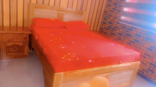 uma cama de madeira com lençóis vermelhos num quarto em La fierté em Ziguinchor