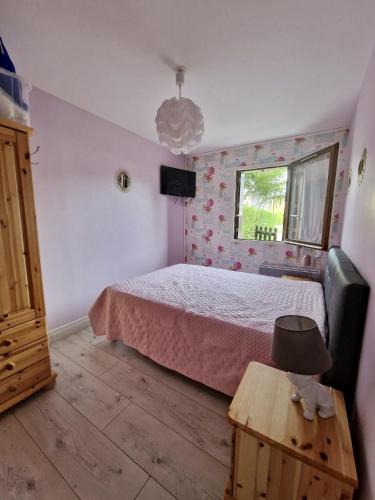 une chambre avec un lit, une table et une fenêtre dans l'établissement Rez-de-jardin près de la mer, à Cabourg