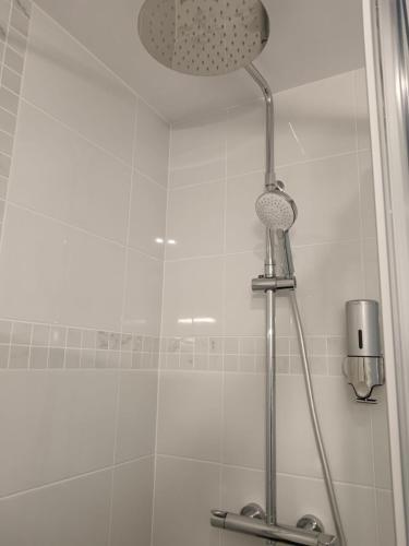 une douche avec pommeau de douche dans une salle de bain dans l'établissement Au jardin Parisien, à Argenteuil