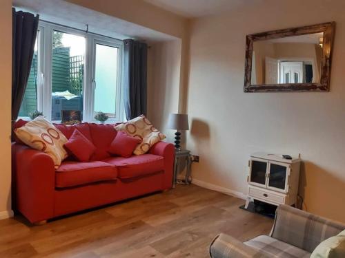een woonkamer met een rode bank en een tv bij Tor View Getaway in Glastonbury in Glastonbury