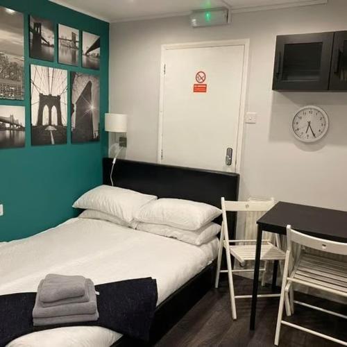 een slaapkamer met een bed en een tafel en een klok bij Vika Residence Deluxe Apartments Wednesbury Holiday Resort in Wednesbury
