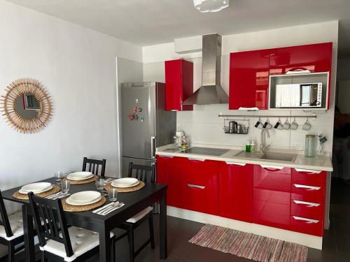 une cuisine avec des placards rouges et une table avec des chaises dans l'établissement Apartamento La Mar, à Puerto de Santiago