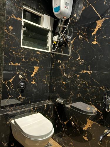 a bathroom with a toilet and a black marble wall at Airport Hotel Relax Inn in Nagpur