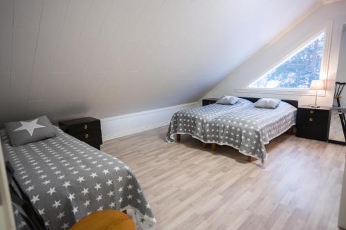 1 dormitorio en el ático con 2 camas y ventana en AaltoSahan huvila, en Orivesi