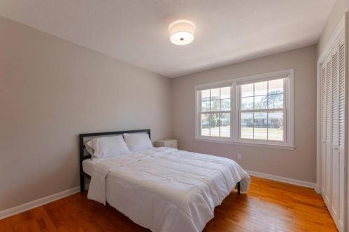 a white bedroom with a bed and a window at Spacious Midtown Ranch- 10 min to Wrightsville in Wilmington