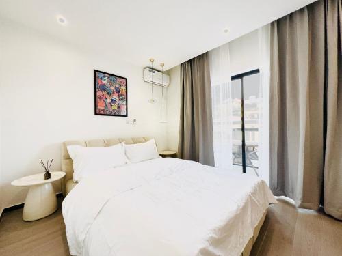 Un dormitorio con una gran cama blanca y una ventana en Japoma Secret Garden, en Douala