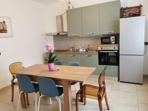 une cuisine avec une table et des chaises et un réfrigérateur blanc dans l'établissement INES HOME tra lago e montagna - Lago d'Iseo, à Pisogne